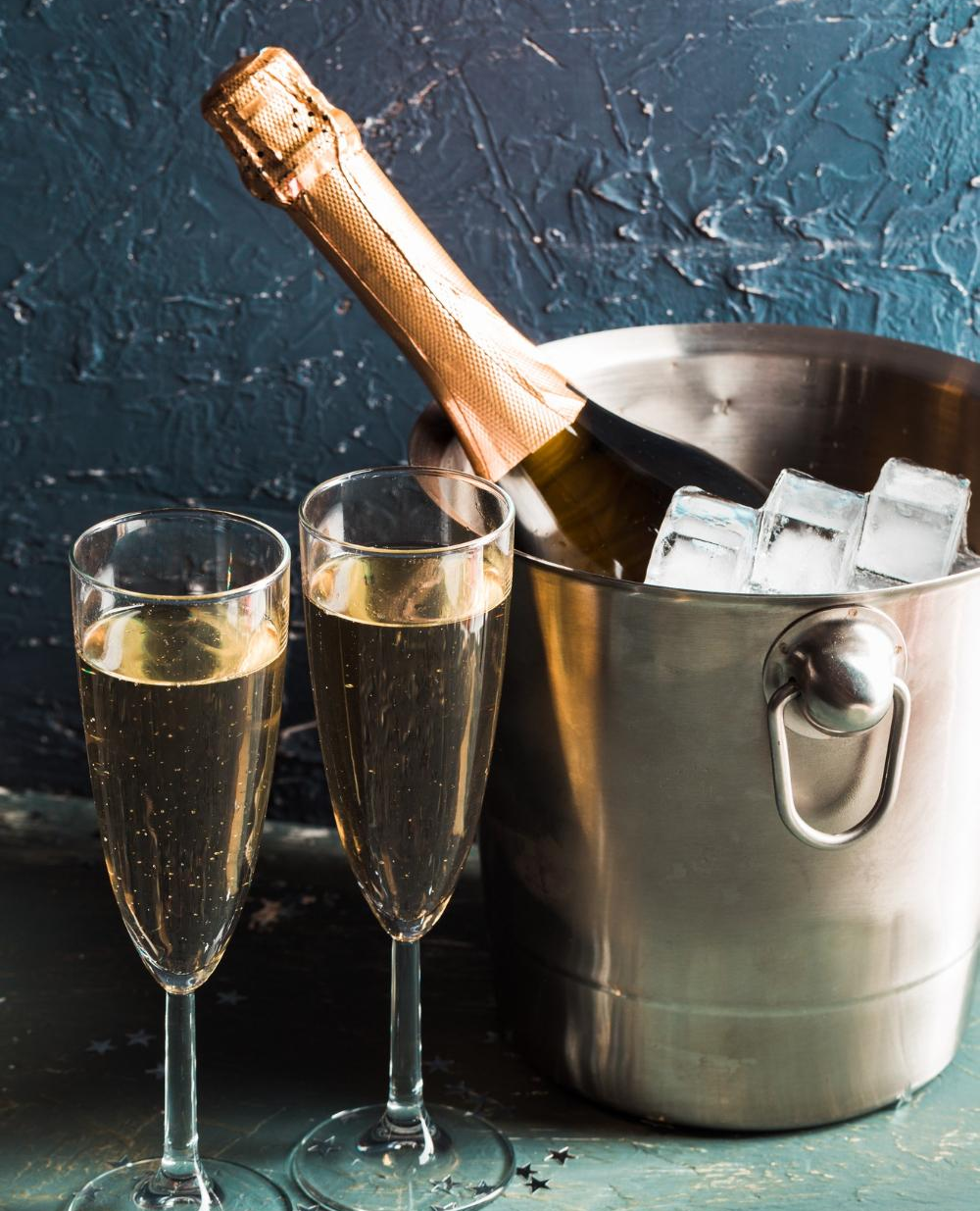 Champagne glasses next to a bottle of Champagne in a bucket of ice